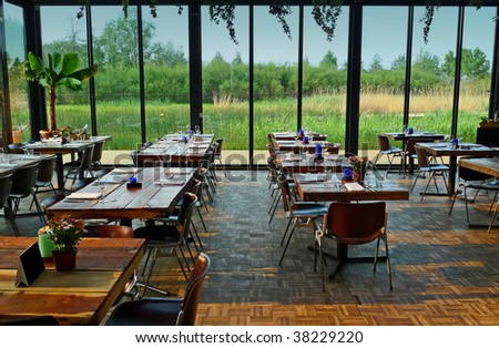 Dining hall with glass walls overlooking a wet garden