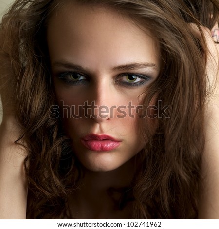 Attractive female gazing into the camera with hands in her hair