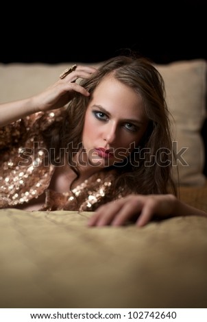 Attractive female, on bed with hand in hair, looking into the camera, seductive expression