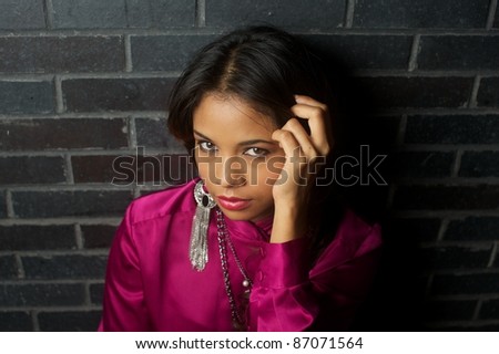 Attractive Asian female against brick wall gazing at the camera