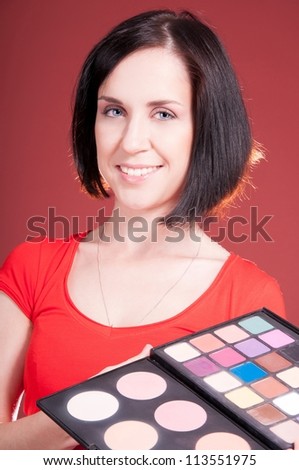 Beautiful young woman holding different make-up shadow and rouge
