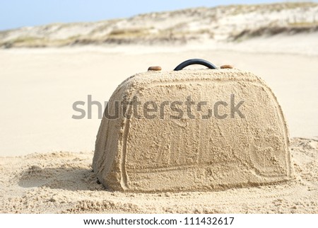Suitcase on remote beach made out of sand. There is loads of space for your writing