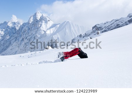 Young man diving head first into untouched powder snow with panorama of mountains in background