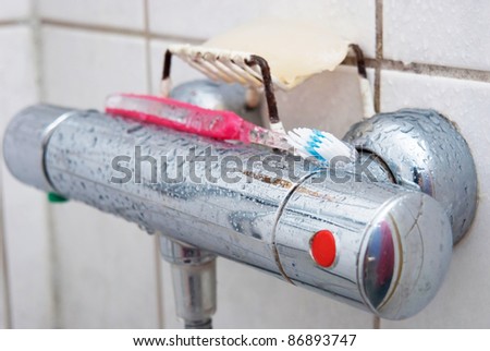 Showering controls with toothbrush and soap. there are some drops on the knobs.