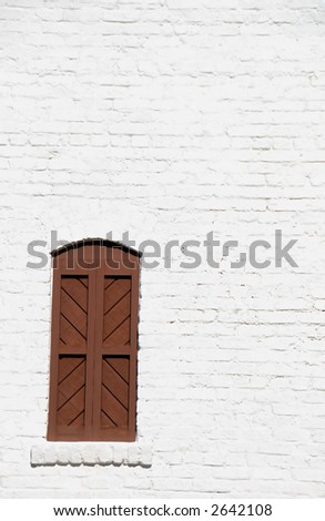 lone brown shutter on white brick