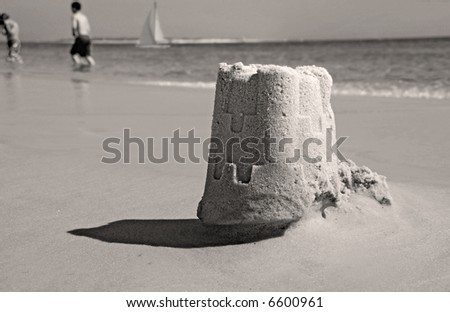 Sand Castle with Kids Playing and Sailboat in Distance