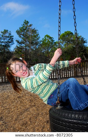 Young Girl in Ponytails Missing front Teeth on Tire Swing