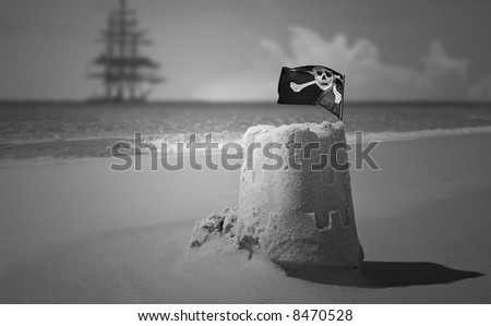 Pirate flag on sand castle with clipper ship in distance