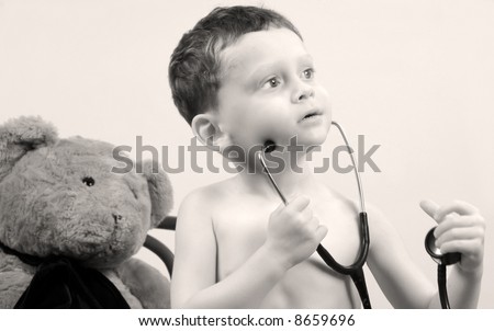 Young toddler boy with stethoscope playing doctor with bear
