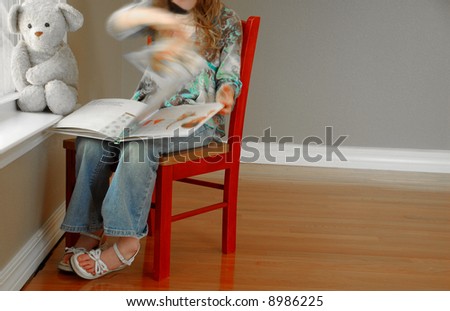 Young girl reading book next to window with her bear