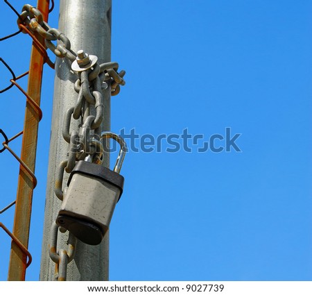 Fence with chain and lock under bright blue sky