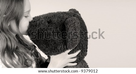 Young girl kissing stuffed toy bear