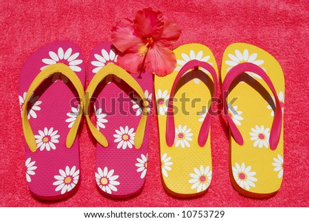 Pretty colorful flipflops on beach towel with hibiscus blossom