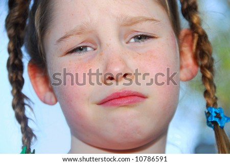 Upset or unhappy young girl with freckles and braids