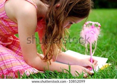Cute young girl using fancy pen to write in journal outside