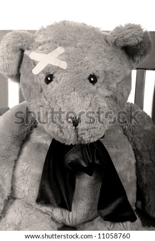 Stuffed bear in chair with bandages over eye