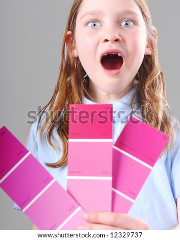 Toothless freckle faced girl excited holding pink paint sample chips