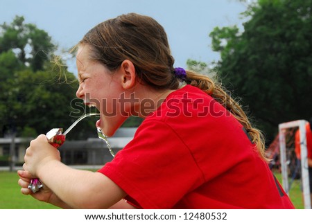 Young soccer playing girl hot and thirsty drinking to rehydrate