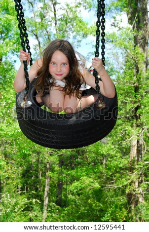 Young girl at outside park swinging on tire swing
