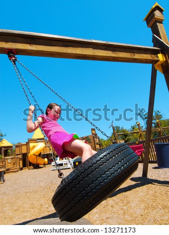 Young girl having fun on tire swing at pretty park