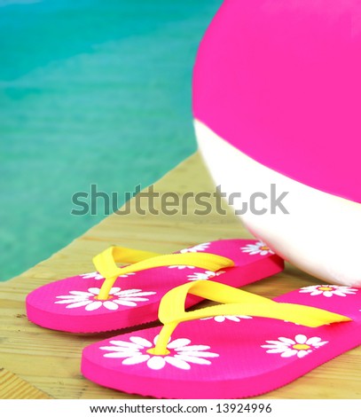 Pink and white beachball with pretty flip flops on dock