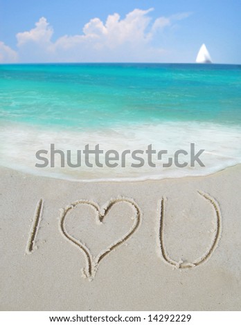I Love You written in sand by gorgeous ocean with sailboat in distance