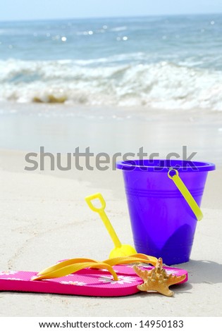 Beach pail, flip flops and starfish on pretty beach