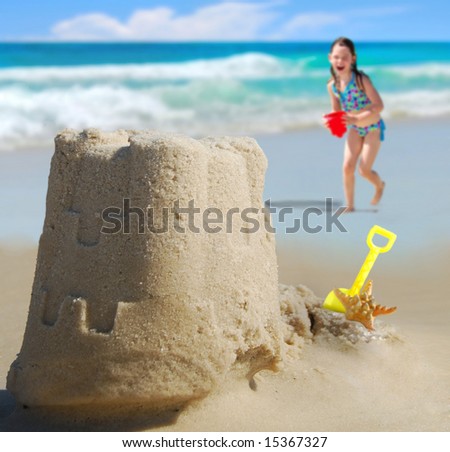 Happy girl running towards Pretty sand castle with ocean in distance