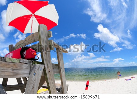 Lifeguard stand and umbrella at beach with girl playing in distance