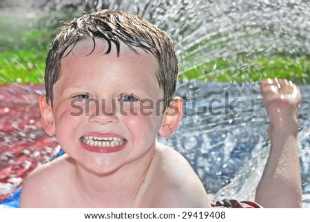 Happy young boy in lawn water play with sprinkler