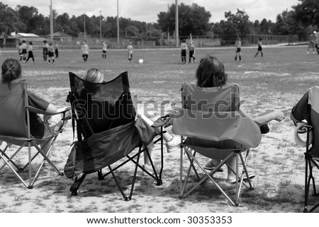 Soccer moms watching young team play on field
