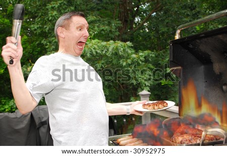 Man grilling on barbeque when flames get out of control - stock photo