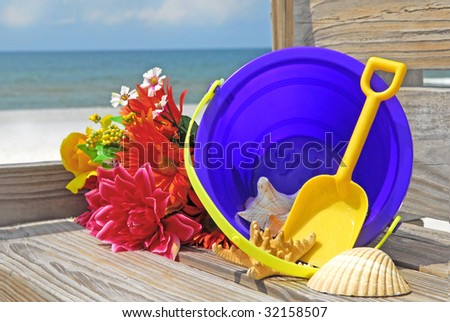 beach sand pail and flowers on boardwalk at ocean
