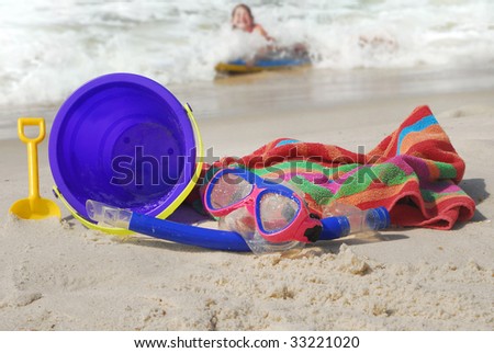young child in water having fun at beach with toys in sand