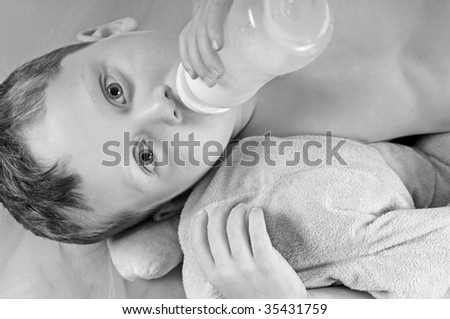 Young toddler ready for nap drinking milk bottle