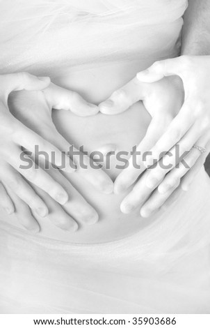 Pregnant woman with exposed belly holding hands with husband