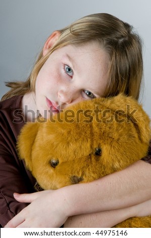 Girl looking sad hugging bear