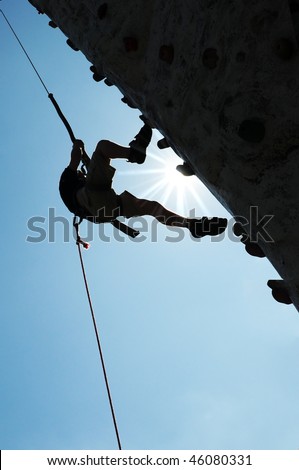 Man on steep climbing wall against blue sky