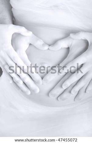 Pregnant woman with exposed belly holding hands with husband