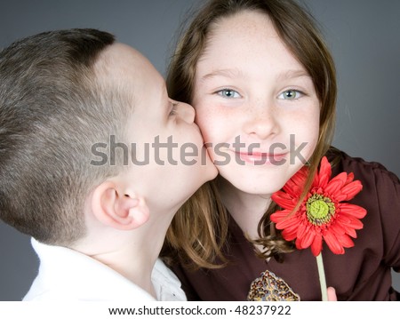 stock photo Young boy kissing girl after giving her flower