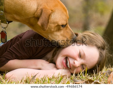 Dog making girl laugh on grass