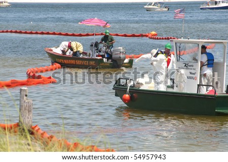 PENSACOLA - JUNE 10:  Oil spill workers in hazardous material suits collect oil-soaked debris on June 10, 2010 from the shores of Naval Air Station, Pensacola, FL.