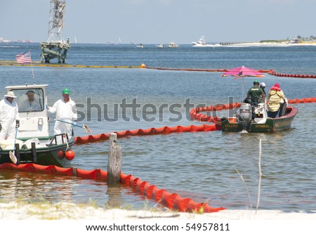 PENSACOLA - JUNE 10:  Oil spill workers clean the beach of Naval Air Station Pensacola, FL as oil washes ashore from the BP spill on June 10, 2010 in Pensacola, Florida.