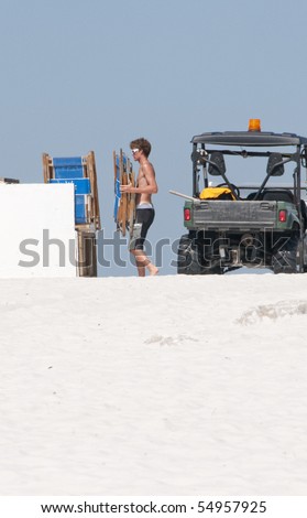 ORANGE BEACH, AL - JUNE 10:  A resort worker puts away lounge chairs early on a beautiful day on June 10, 2010 at Perdido Pass, AL since tourists are away from the beach area.