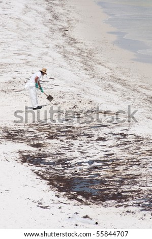 PENSACOLA BEACH - JUNE 23:  A BP oil worker attempts to clean oil covered sand on June 23, 2010 in Pensacola Beach, FL.