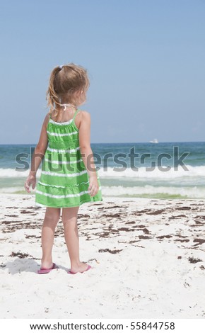 PENSACOLA BEACH - 23 JUNE: An unidentified young girl stands near oil covered sand on June 23, 2010 in Pensacola Beach, FL.
