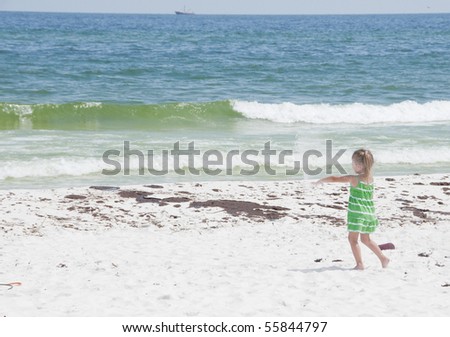 PENSACOLA BEACH - 23 JUNE: An unidentified young girl plays with sand by oil covered sand on June 23, 2010 in Pensacola Beach, FL.
