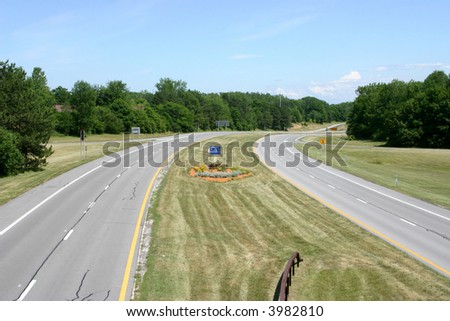Open road with grass and trees but no cars