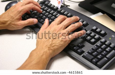 Hands on keyboard.  Focus is on keyboard with hands slightly blurred to show movement