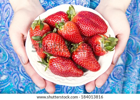 plate with strawberries in hands of the girl
